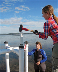 Graduate student Cassie Gurbisz hammers away at the support pipes that will hold a water sampling station, while research technician Debbie Hinkle lends a steadying hand. Credit: Dale Booth