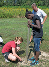 Two classmates use a device called a transparency tube to measure Secchi depth. Credit: Daniel Strain