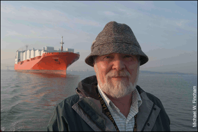 Dave Van Metre in raincoat and hat with Taiko in background