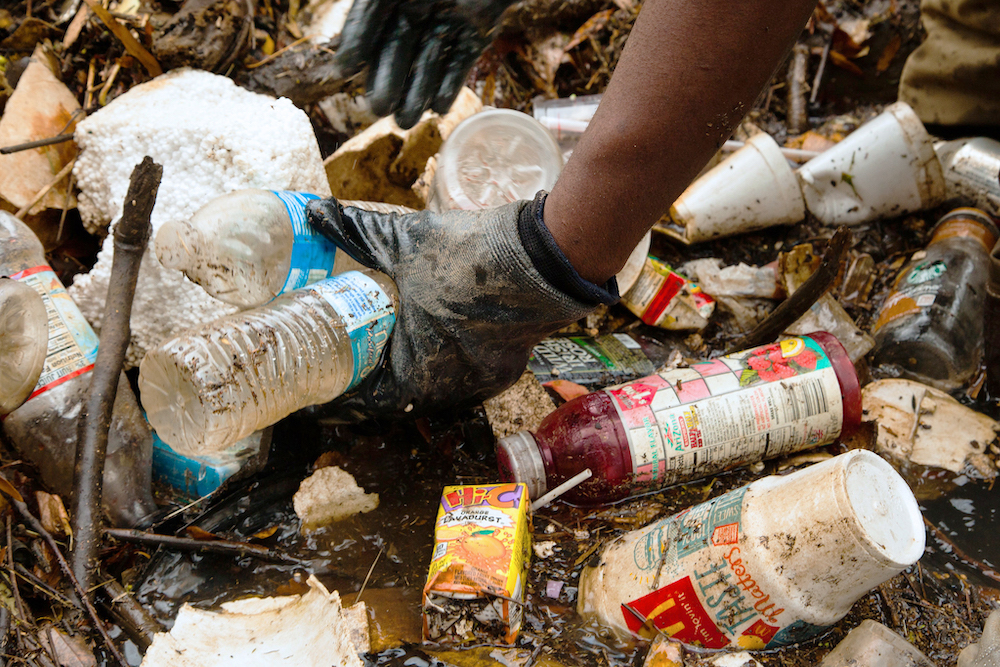 Gloved hand reaches into a pile of debris.