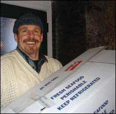 Gaylord Clark holding a box of frozen fish, photograph by Jessica Smits
