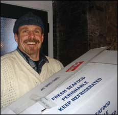 Gaylord Clark holding a box of frozen fish, photograph by Jessica Smits