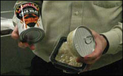 Tom Rippen holding 2 cans of crab meat, Photograph by Erica Goldman