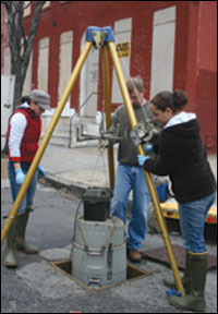 Lowering automated water sampler into a storm drain- photo by Erica Goldman