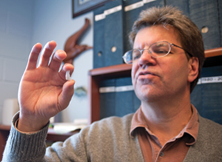 David Secor admires a striped bass otolith. Credit: Daniel Strain
