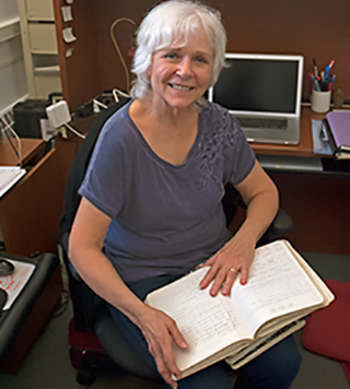 Carole Derry holds a stack of handwritten maintenance logs. Photograph, Daniel Pendick