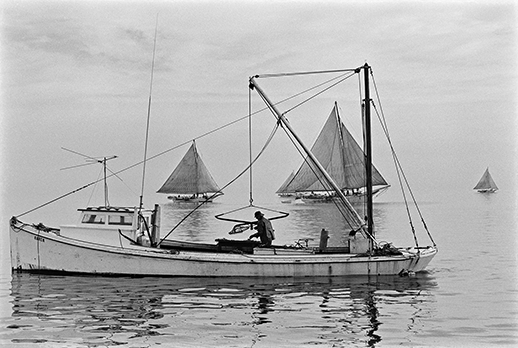 Two kinds of oystering: a patent tonger with his hydraulic rig. Photograph courtesy of the Chesapeake Bay Maritime Museum