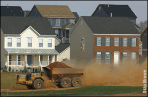 dump truck racing past new houses and kicking up dirt