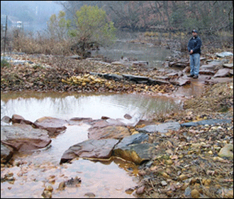 Drew Koslow standing near an expensive river restoration