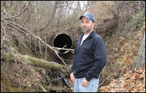 Drew Koslow standing near a stormwater pipe
