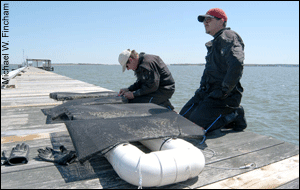 Two people making an oyster float to grow oysters.